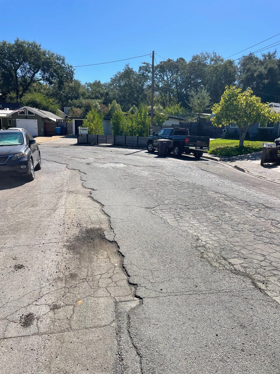 Road with a long open crack along a trench seam and a crumbling dark pothole