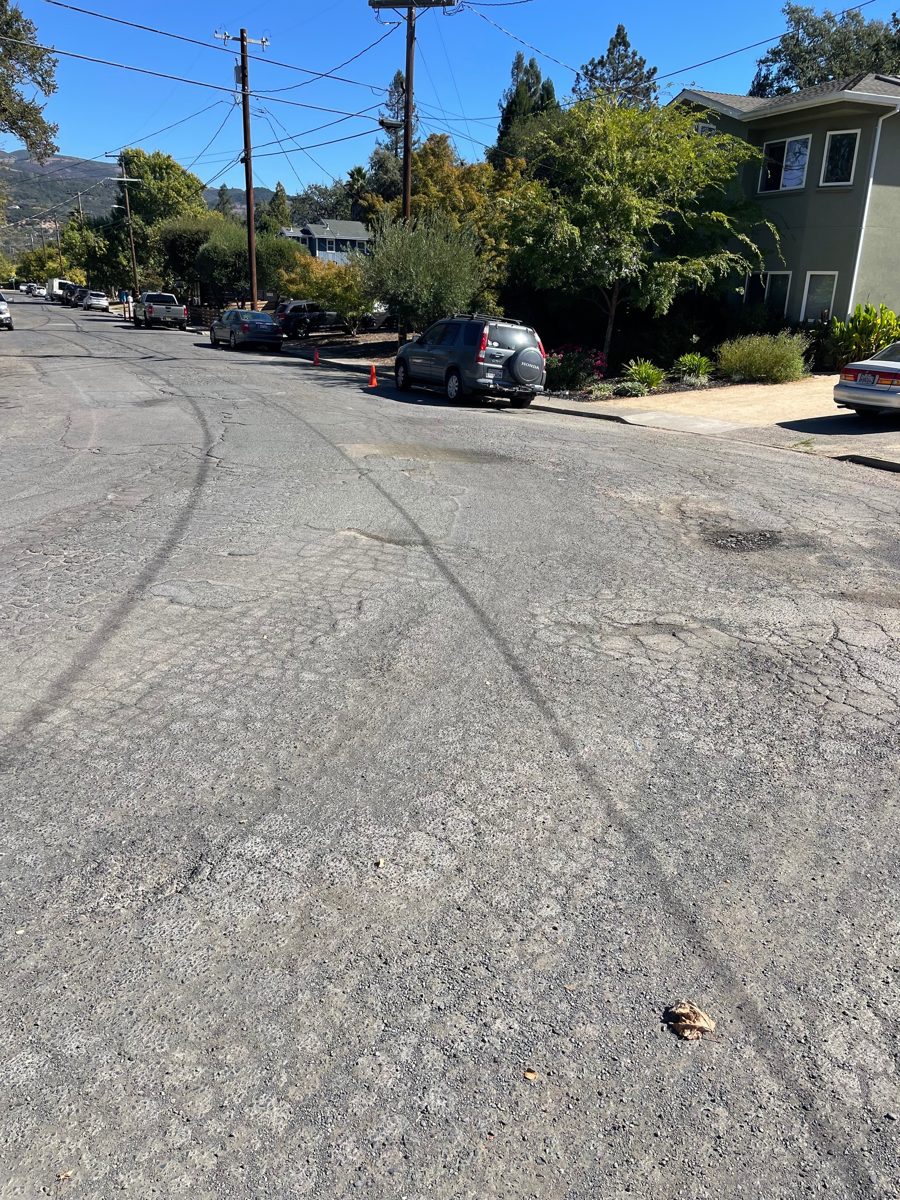 Intersection with worn, patched and cracked pavement and loose gravel