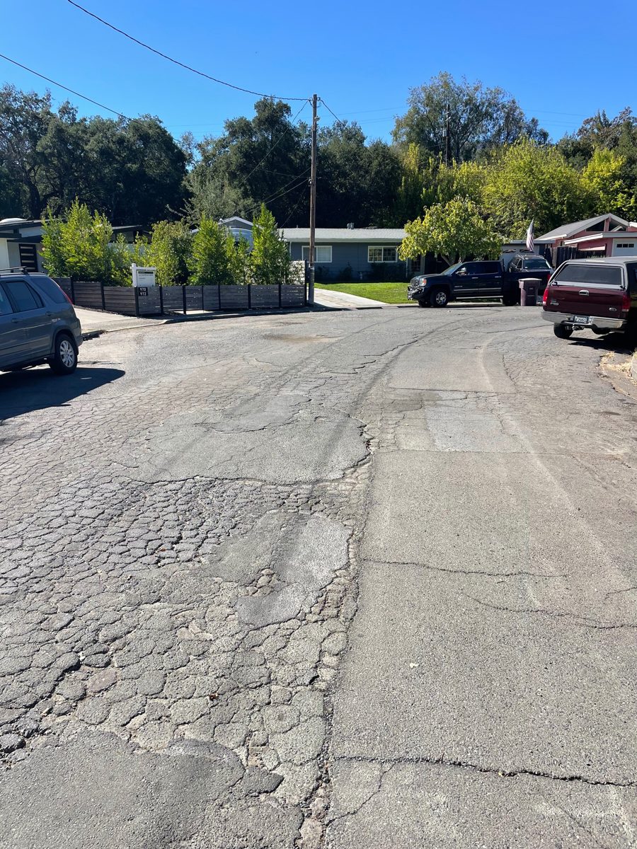 Street curve with block-pattern cracking on one side and a patched strip down the middle